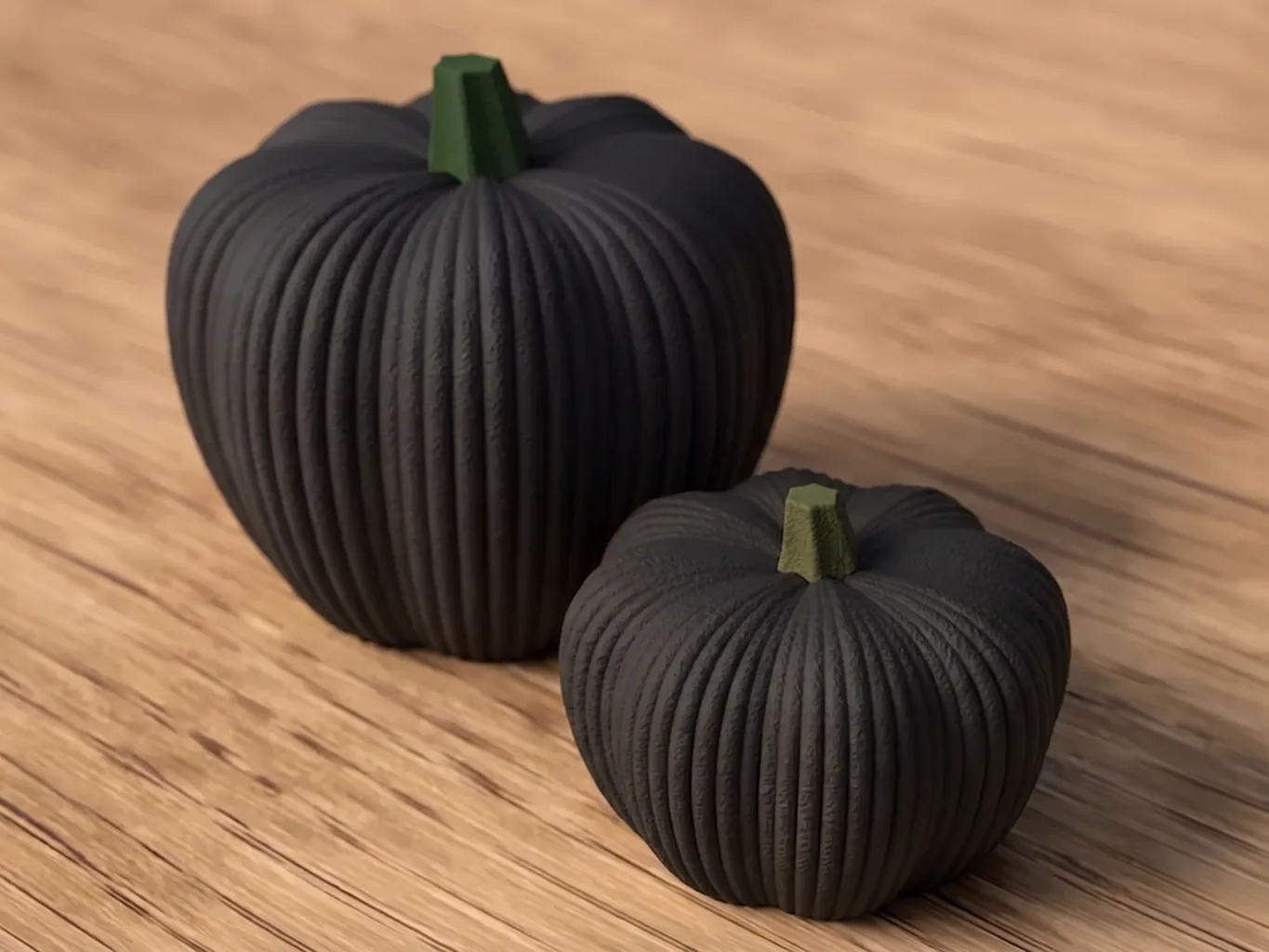 Two decorative 3D printed pumpkins in matte black, large and small models, ribbed body and green stem, placed on an oak table